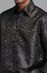 A man wears the Manzini MANZINI MZT-100 Paisley Long Sleeve Satin Black Shirt with links, featuring a shiny, intricate paisley pattern. Only his upper body is visible.