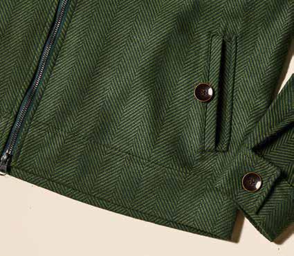 An individual wearing the Inserch Olive Wool Blend Herringbone Jacket (JS263-19) is seen paired with blue jeans and brown sneakers, standing against a beige background.