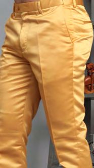 A person wearing Manzini MP-400 Gold Satin Pants from Manzini, featuring belt loops, stands next to a gray structure.