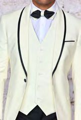 A person dressed in the Insomnia Sunset 3PC Slim Fit Cream Black Tuxedo Suit, featuring a cream-colored jacket with black trim, a reversible vest that matches perfectly, and a sleek black bow tie.