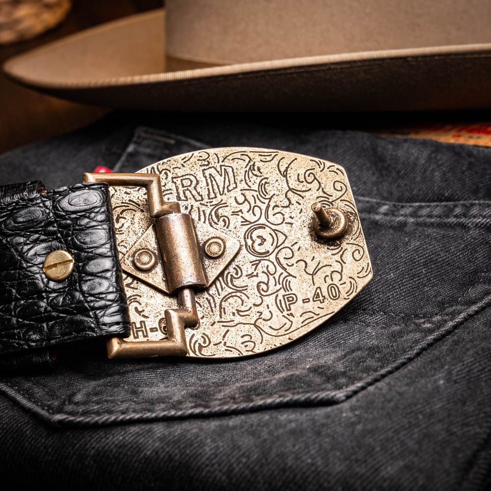 The Iowa Belt Black by Marco Di Milano is crafted from genuine black caiman skin with a crocodile texture, featuring a bold gold "MD" buckle and embossed branding—an eye-catching Western belt for any outfit.