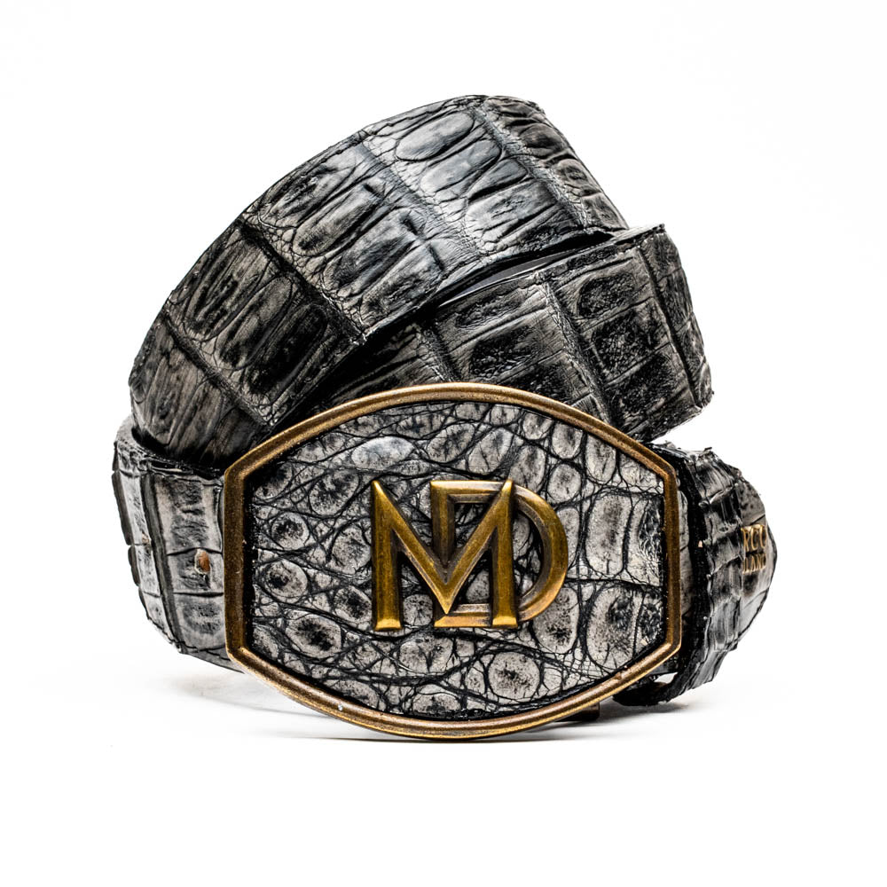 The Marco Di Milano Iowa Belt Stone Gray features genuine caiman skin and a bold gold "MD" buckle on a textured background, combining luxury with standout Western style.