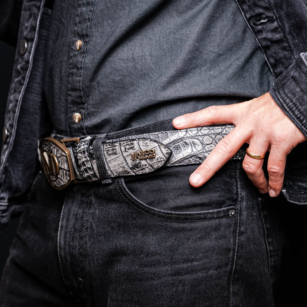 The Marco Di Milano Iowa Belt Stone Gray features genuine caiman skin and a bold gold "MD" buckle on a textured background, combining luxury with standout Western style.