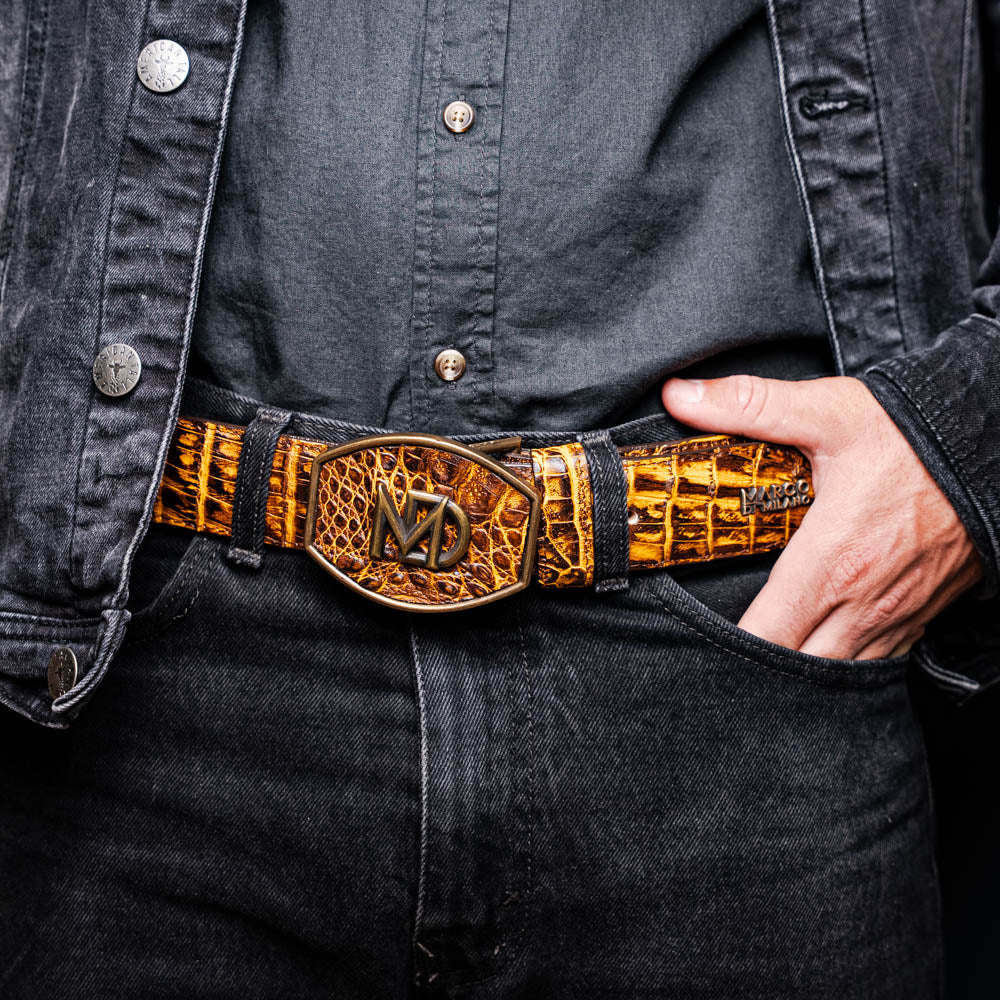 The Iowa Belt Mustard Brown by Marco Di Milano features genuine caiman crocodile leather and a bold gold "MD" buckle, elegantly displayed on a white background—showcasing the brand's signature luxury style.