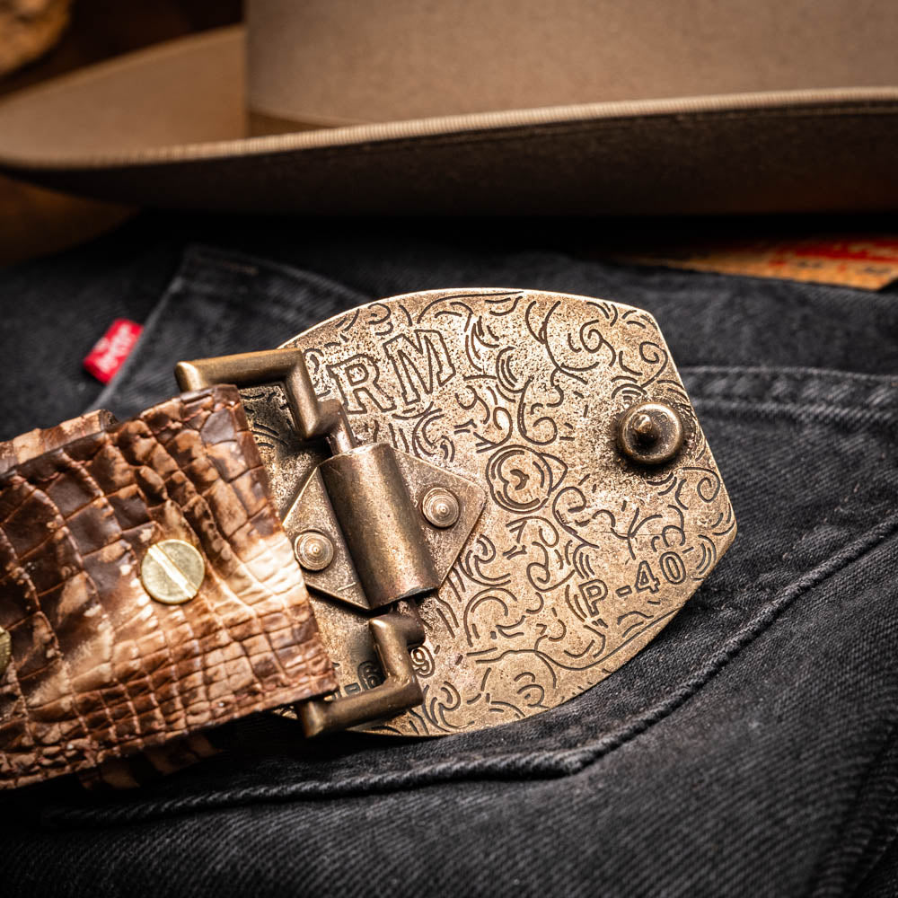 The Marco Di Milano Iowa Belt Stone Brown features genuine caiman crocodile leather, a gold "MD" buckle, and "Marco Milano" engraved on the side, evoking a classic western style against a white background.
