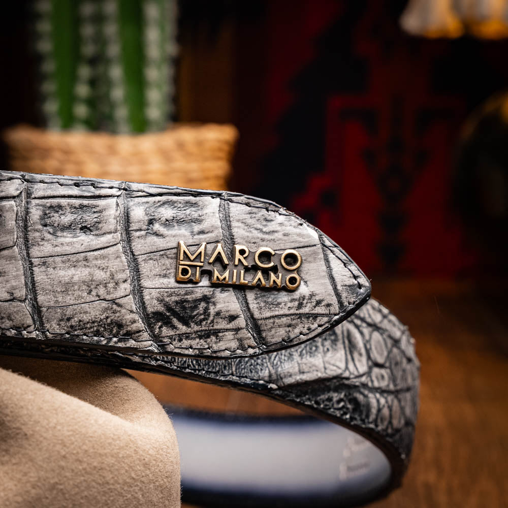The Marco Di Milano Iowa Belt Stone Gray features genuine caiman skin and a bold gold "MD" buckle on a textured background, combining luxury with standout Western style.
