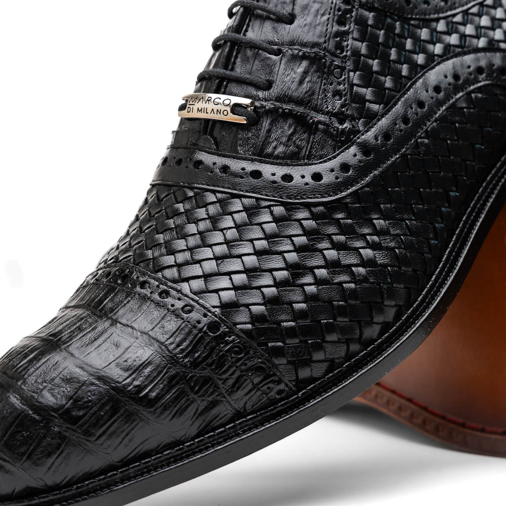 A pair of luxury "John Black" dress oxfords by Marco Di Milano, crafted from genuine caiman crocodile leather with intricate detailing and brown leather soles—one upright, the other resting sideways beneath it.