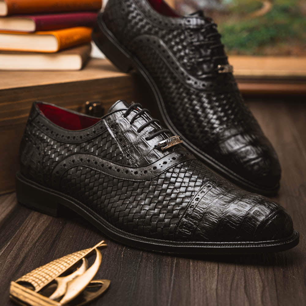 A pair of luxury "John Black" dress oxfords by Marco Di Milano, crafted from genuine caiman crocodile leather with intricate detailing and brown leather soles—one upright, the other resting sideways beneath it.