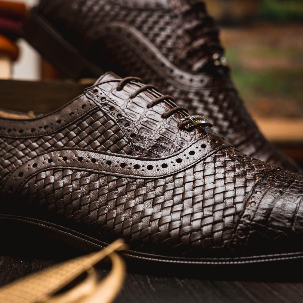 A pair of John Brown luxury dress oxfords by Marco Di Milano in brown woven calfskin leather with brogue detailing; one shoe upright, the other displays the sole and "Marco Di Milano" branding.