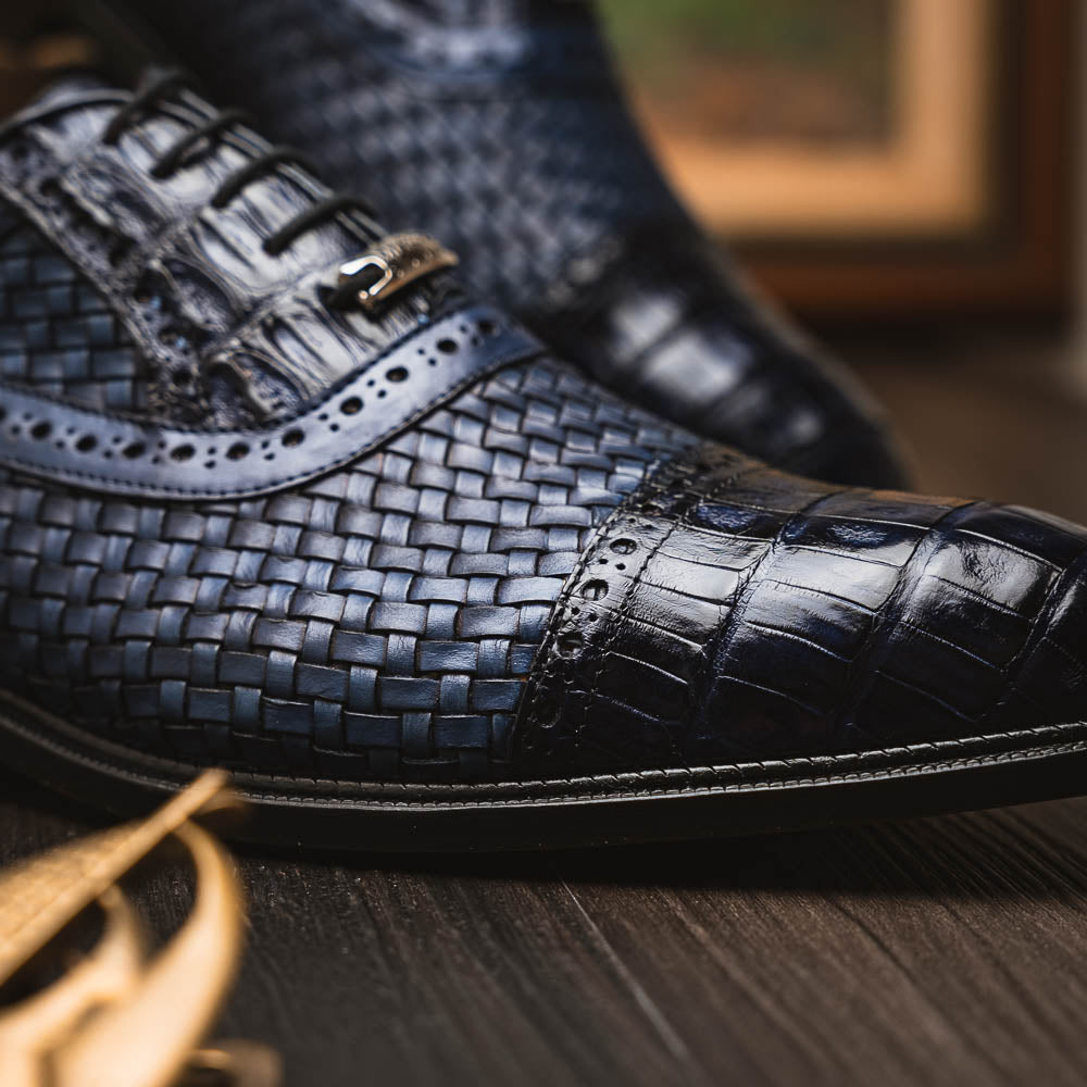 Introducing the Marco Di Milano John Navy: luxury dark blue woven oxford shoes in genuine caiman crocodile leather, with one shoe showing the sole and the other upright.