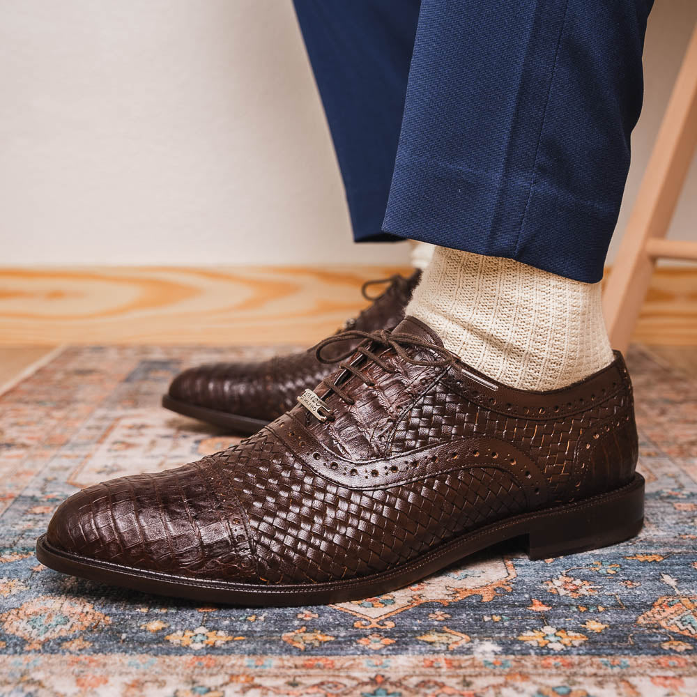 A pair of John Brown luxury dress oxfords by Marco Di Milano in brown woven calfskin leather with brogue detailing; one shoe upright, the other displays the sole and "Marco Di Milano" branding.