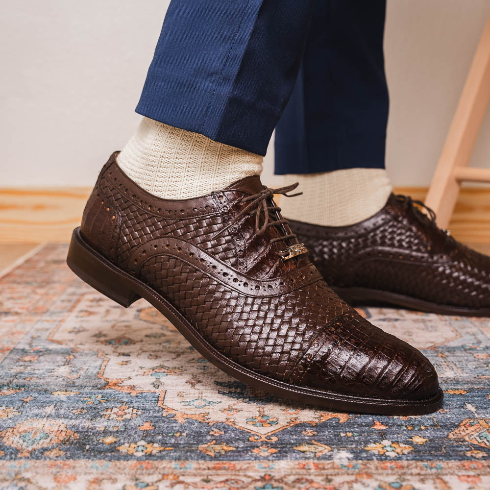 A pair of John Brown luxury dress oxfords by Marco Di Milano in brown woven calfskin leather with brogue detailing; one shoe upright, the other displays the sole and "Marco Di Milano" branding.