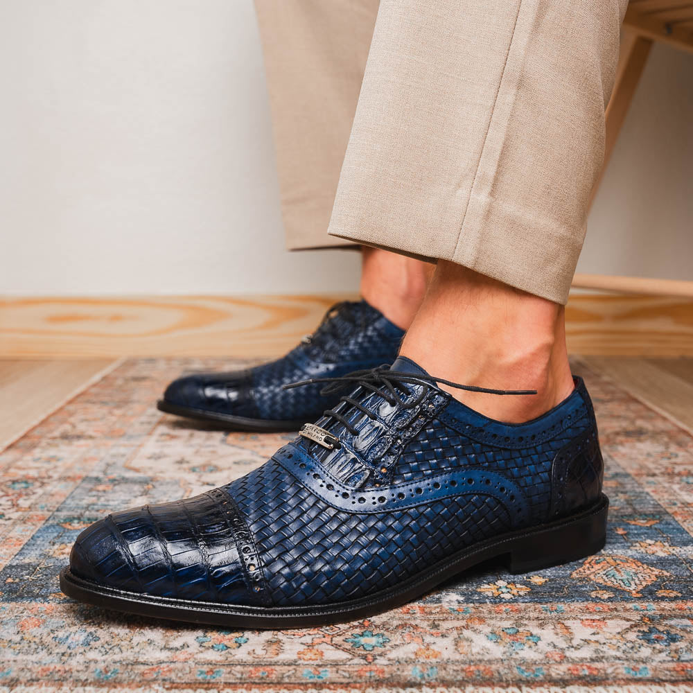 Introducing the Marco Di Milano John Navy: luxury dark blue woven oxford shoes in genuine caiman crocodile leather, with one shoe showing the sole and the other upright.