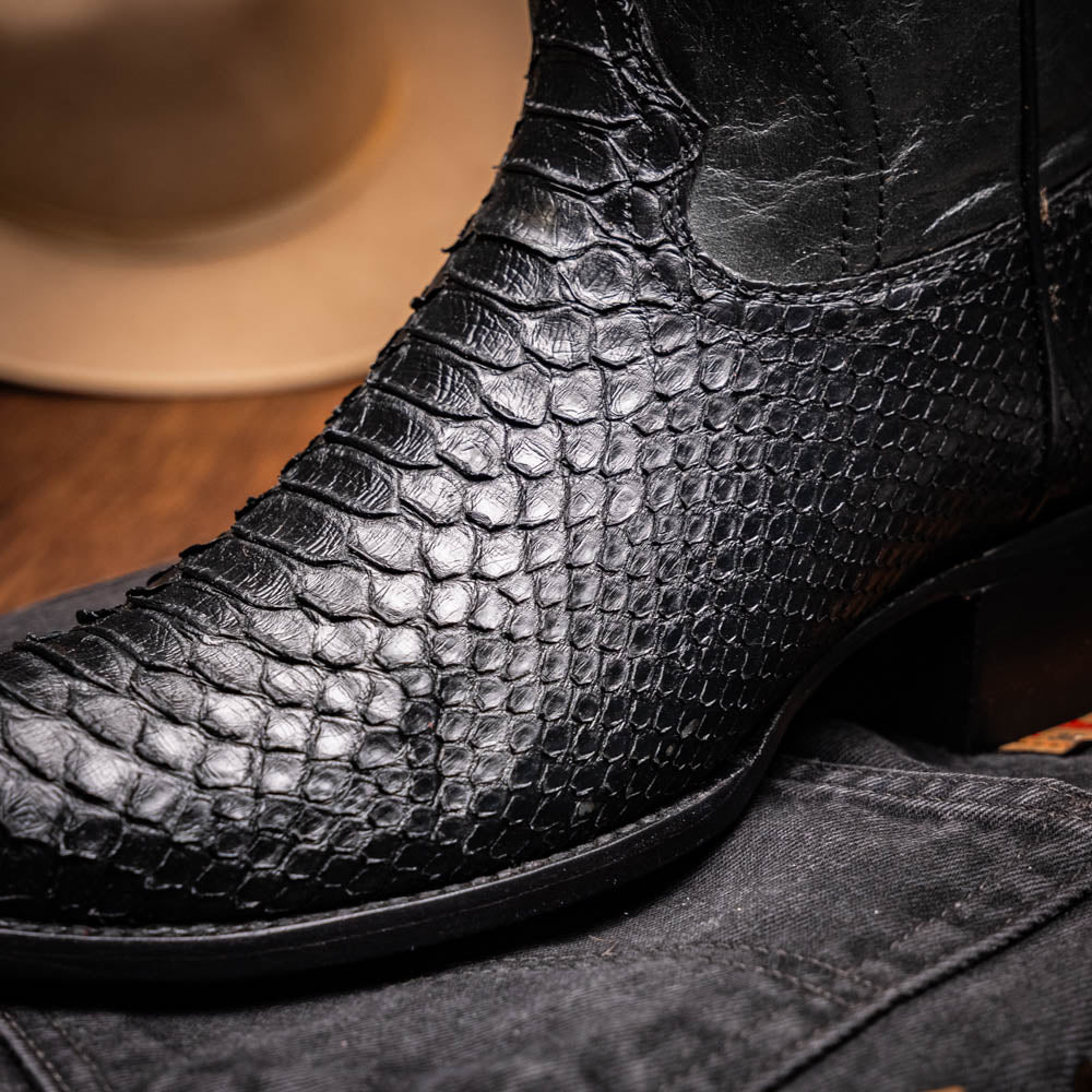 A pair of Kansas Black genuine python boots by Marco Di Milano, one upright and one on its side showing the branded sole.