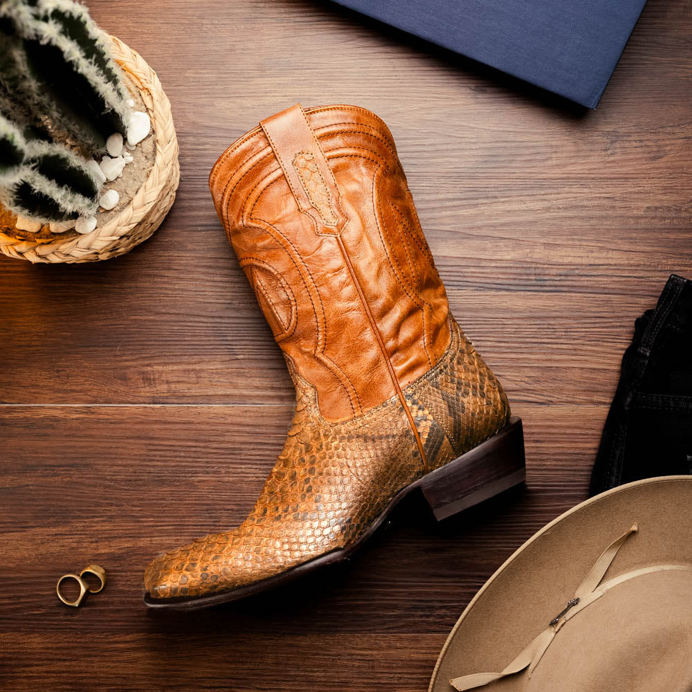A pair of Kansas Cognac cowboy boots by Marco Di Milano in brown genuine python skin, featuring textured scales—one boot upright, the other showing the branded sole.