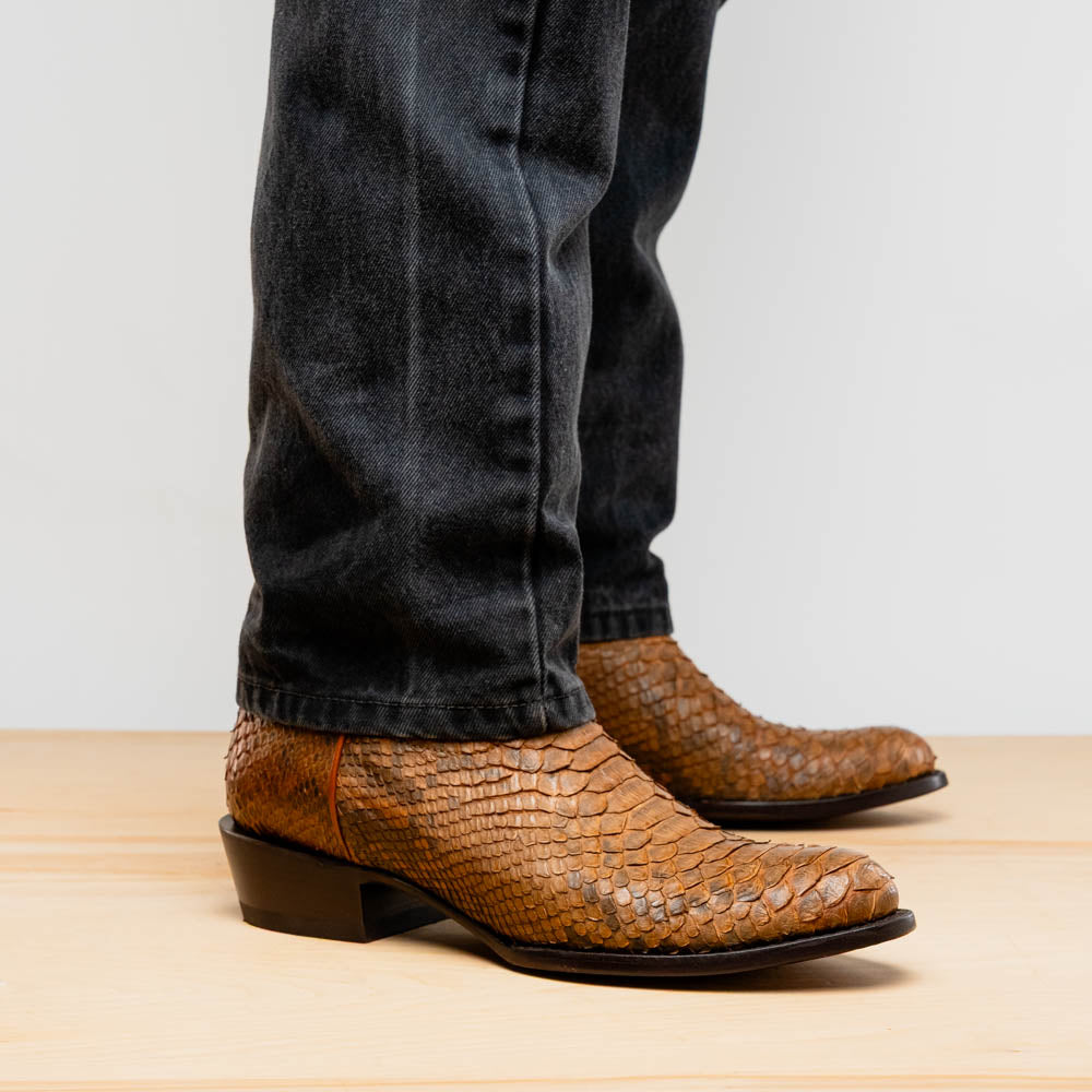 A pair of Kansas Cognac cowboy boots by Marco Di Milano in brown genuine python skin, featuring textured scales—one boot upright, the other showing the branded sole.