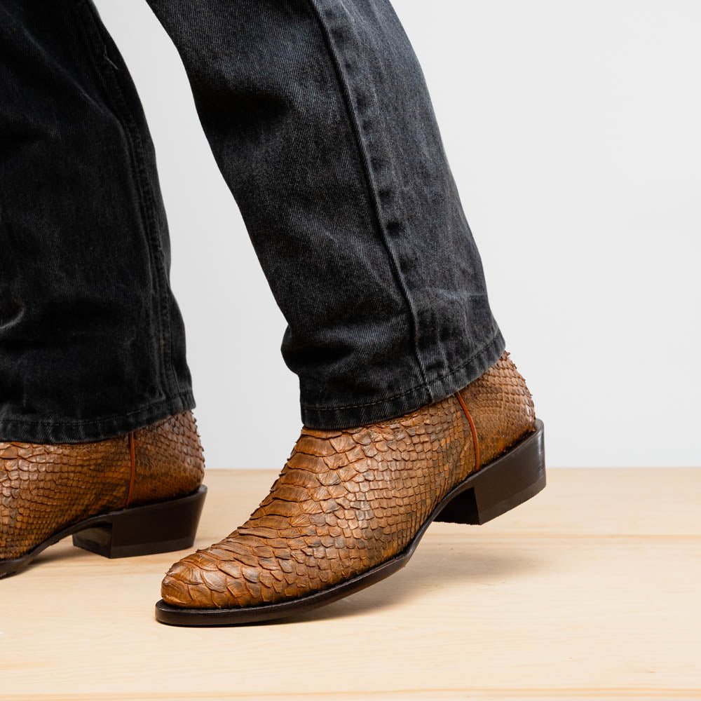 A pair of Kansas Cognac cowboy boots by Marco Di Milano in brown genuine python skin, featuring textured scales—one boot upright, the other showing the branded sole.