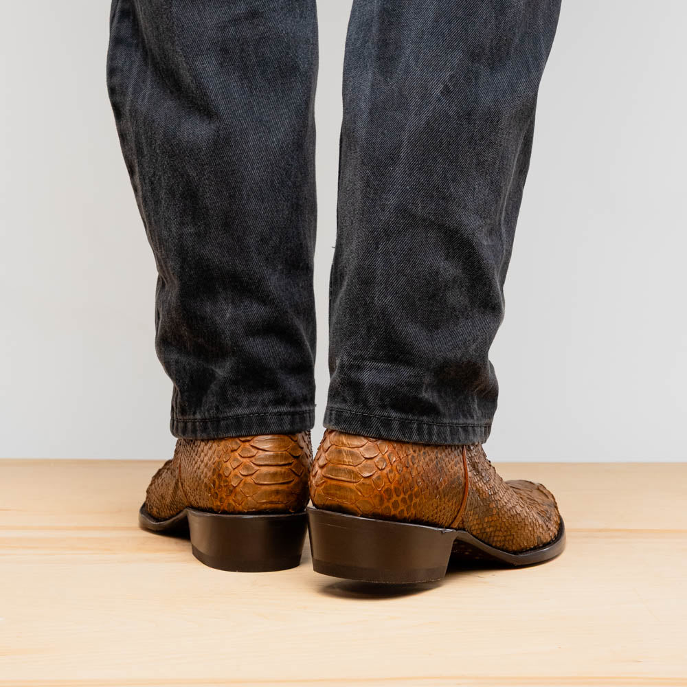 A pair of Kansas Cognac cowboy boots by Marco Di Milano in brown genuine python skin, featuring textured scales—one boot upright, the other showing the branded sole.