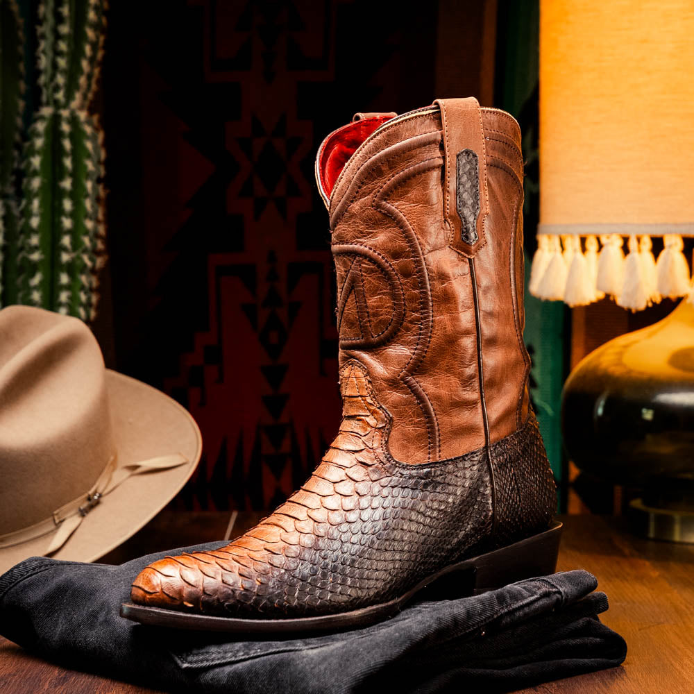 A pair of Kansas Lisboa boots by Marco Di Milano in brown and black python leather, featuring textured scales; one boot stands upright while the other displays the branded sole with "Marco Di Milano" text.