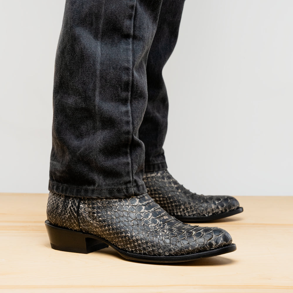 A pair of Kansas Stone White Western cowboy boots by Marco Di Milano, featuring textured, snakeskin-like leather and decorative stitching; one boot stands upright, the other shows the branded sole.