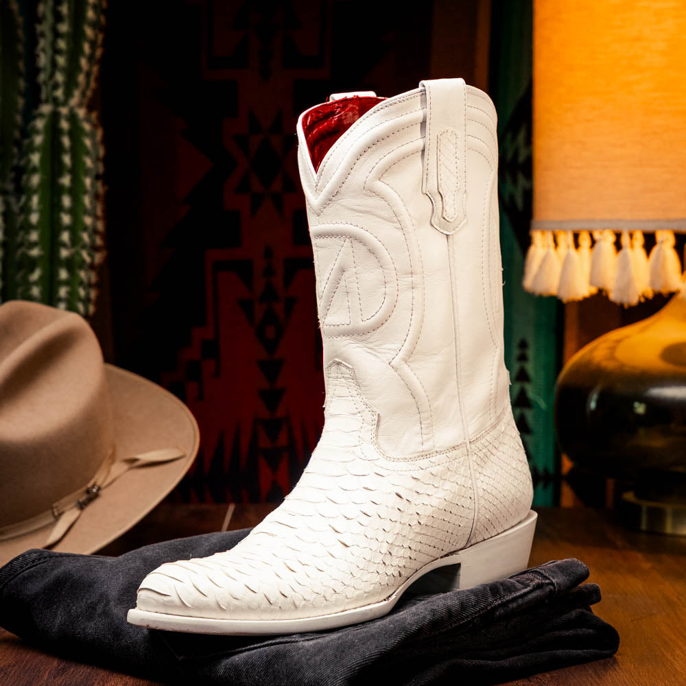 A pair of Kansas White cowboy boots by Marco Di Milano in white textured python skin with pointed toes and low heels; one boot stands upright while the other shows the branded sole.