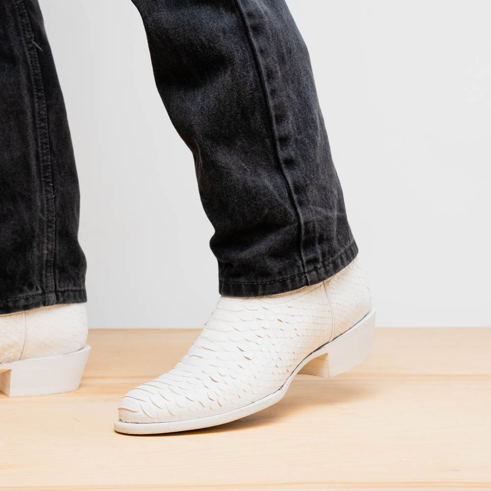 A pair of Kansas White cowboy boots by Marco Di Milano in white textured python skin with pointed toes and low heels; one boot stands upright while the other shows the branded sole.