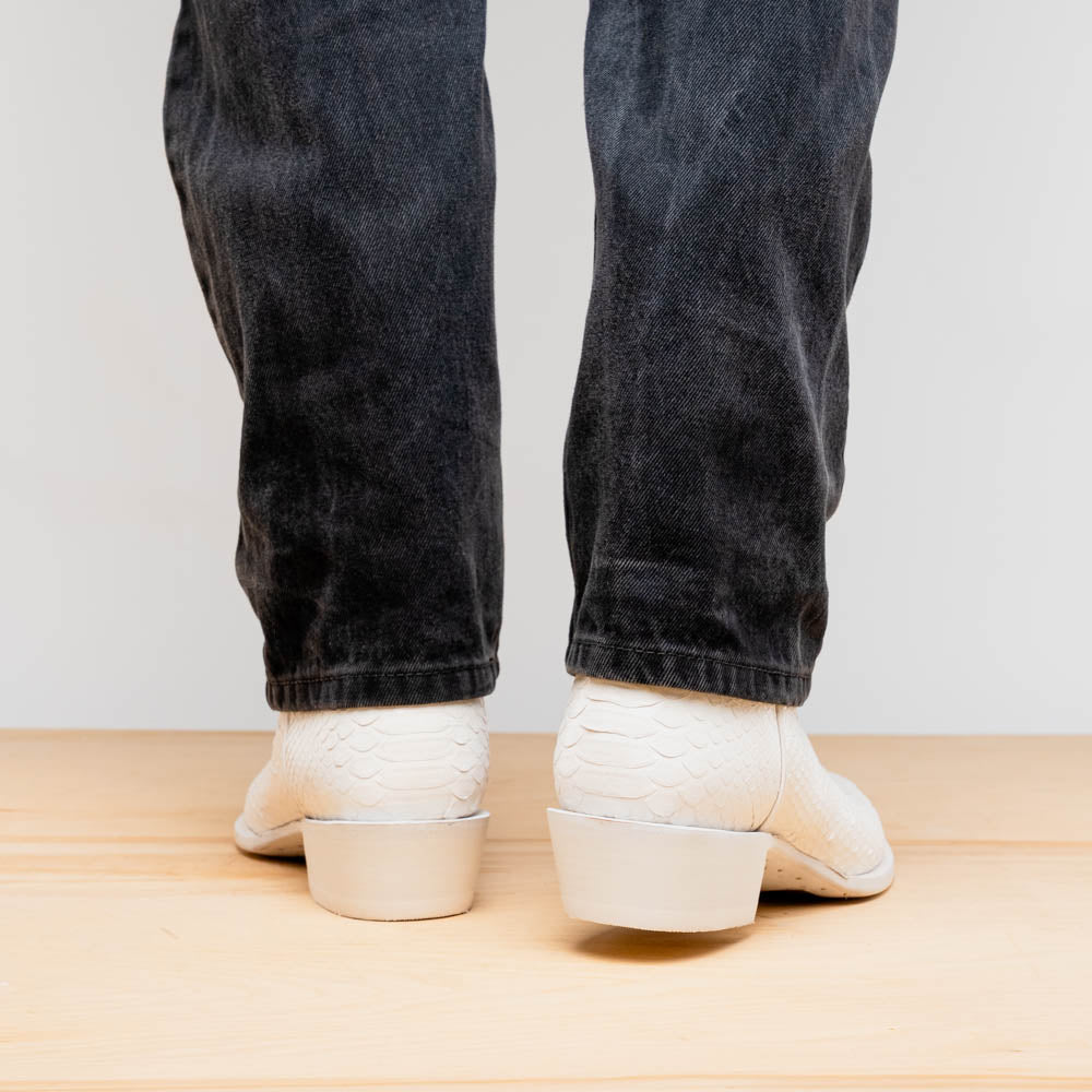 A pair of Kansas White cowboy boots by Marco Di Milano in white textured python skin with pointed toes and low heels; one boot stands upright while the other shows the branded sole.
