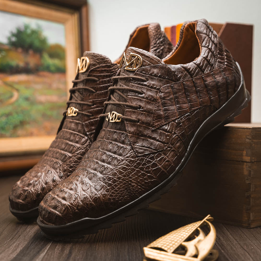 The Kratos Brown by Marco Di Milano features genuine caiman crocodile leather, a hand-painted brown finish, black soles, and gold lace accents—ideal luxury dress shoes for the discerning wearer.