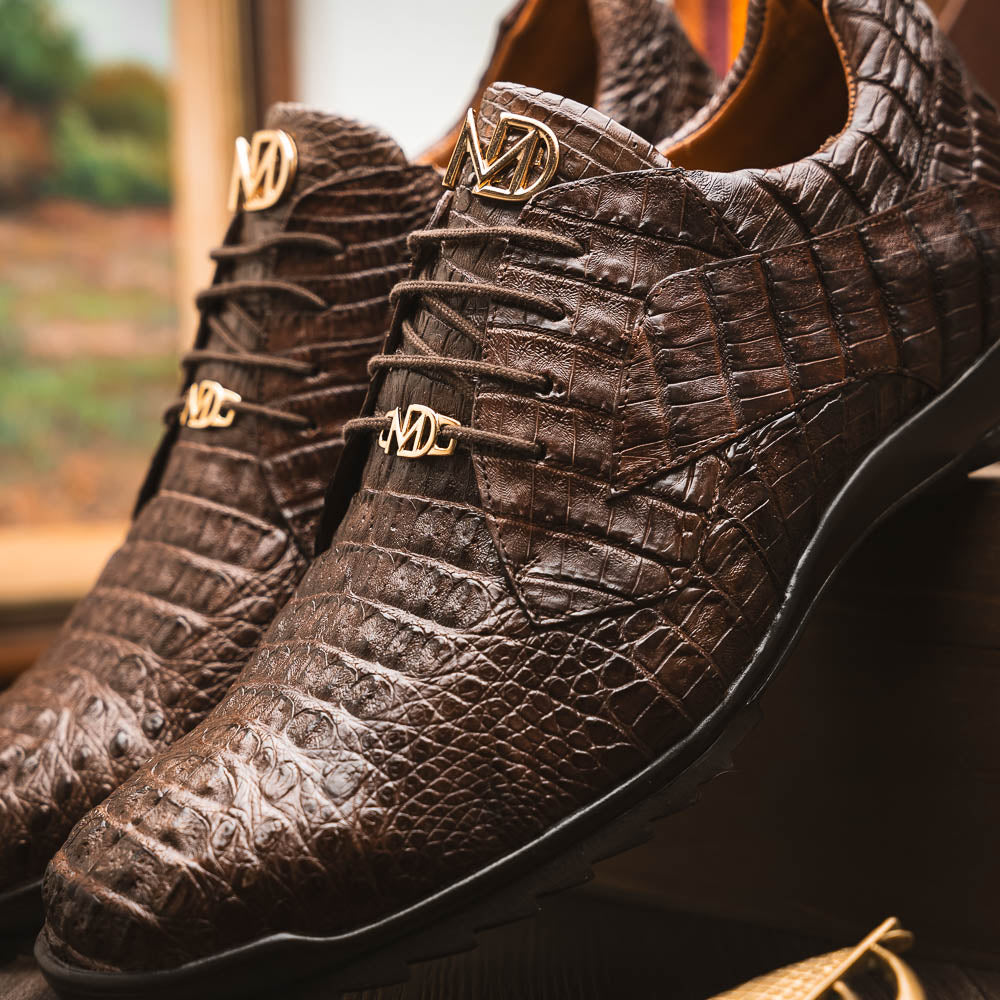 The Kratos Brown by Marco Di Milano features genuine caiman crocodile leather, a hand-painted brown finish, black soles, and gold lace accents—ideal luxury dress shoes for the discerning wearer.