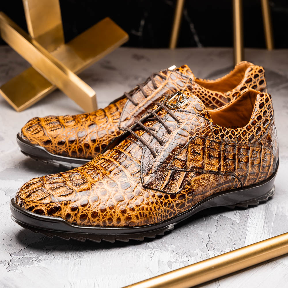 A pair of Kratos Rustic Orix brown crocodile-patterned leather dress shoes by Marco Di Milano, one upright and one tilted to display the textured sole, showcasing luxury footwear against a white background.