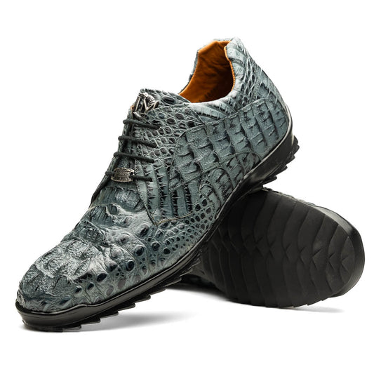 The Kratos Gray by Marco Di Milano are luxury dress shoes in textured gray crocodile-patterned leather with a hand-painted finish and black rubber soles; one shoe stands upright while the other rests on its side.