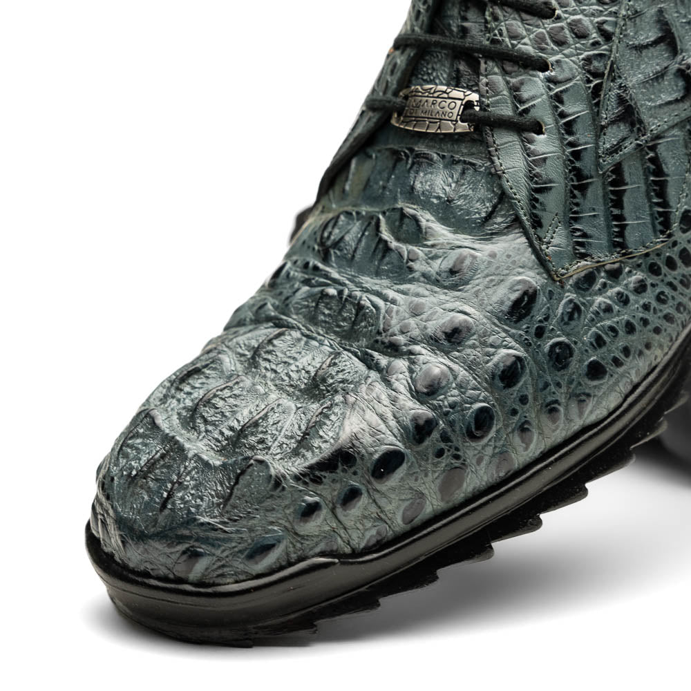 The Kratos Gray by Marco Di Milano are luxury dress shoes in textured gray crocodile-patterned leather with a hand-painted finish and black rubber soles; one shoe stands upright while the other rests on its side.