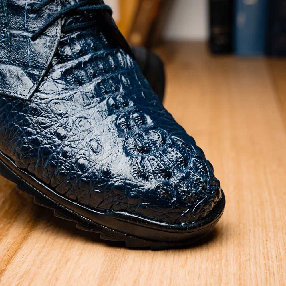 The Kratos Navy by Marco Di Milano: blue hand-painted crocodile-patterned leather dress shoes with black rubber soles—one upright, the other propped—a true statement of luxury footwear.