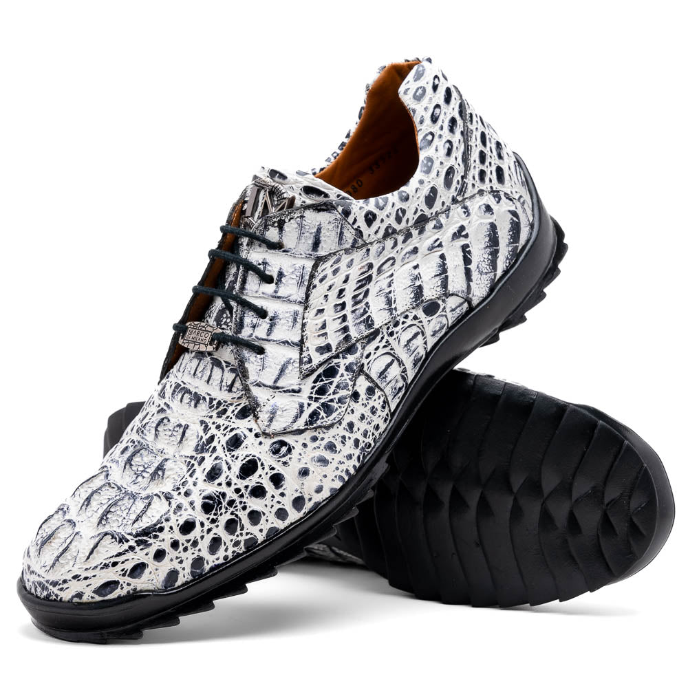 The Marco Di Milano Kratos Newspaper features white and black crocodile-patterned luxury dress shoes with black soles; one shoe stands upright, while the other lies on its side showcasing the hand-painted finish.