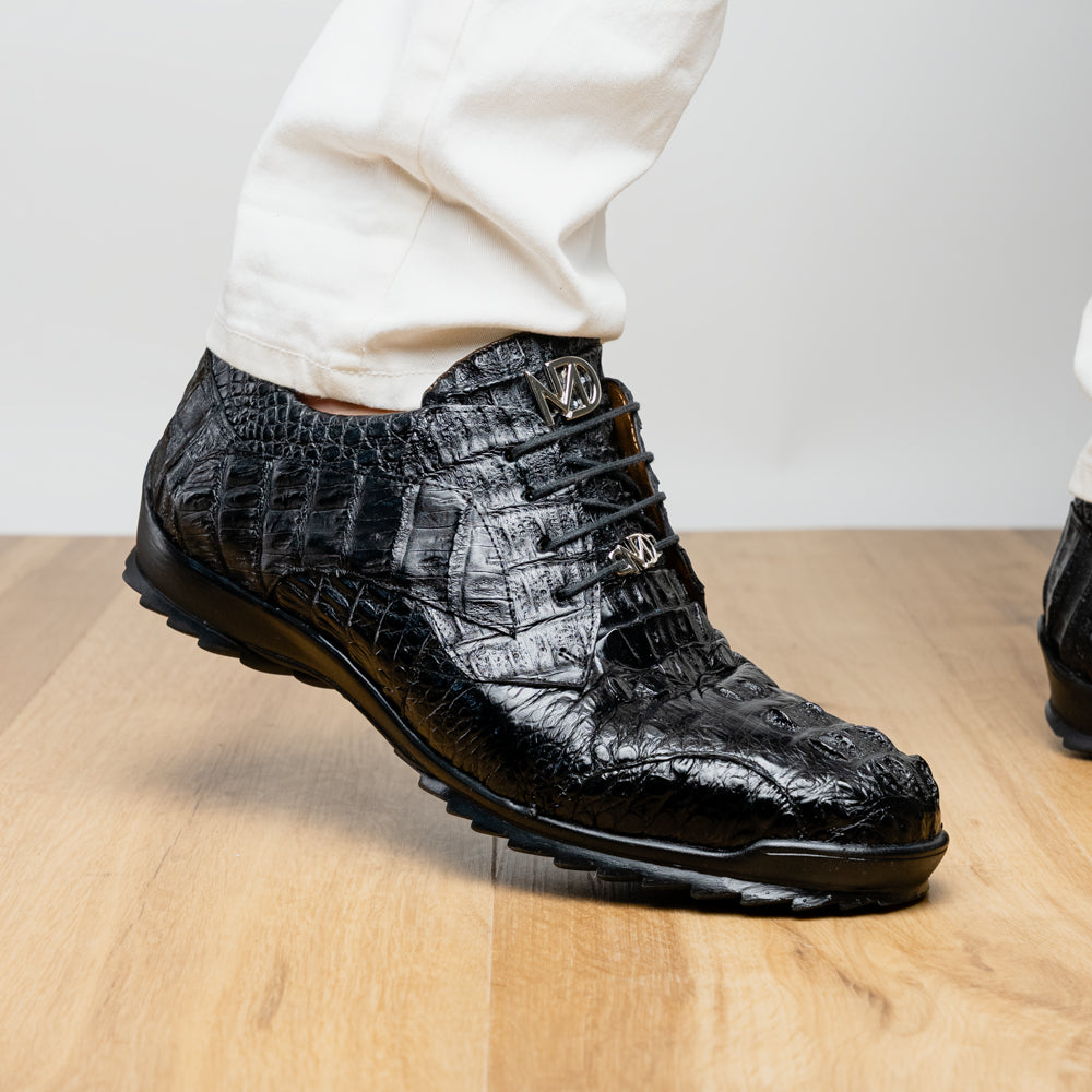 The Kratos Black by Marco Di Milano is a luxury black crocodile-patterned leather dress shoe, featuring a metal logo on the laces. Displayed with one upright and one on its side to showcase the detailed sole.