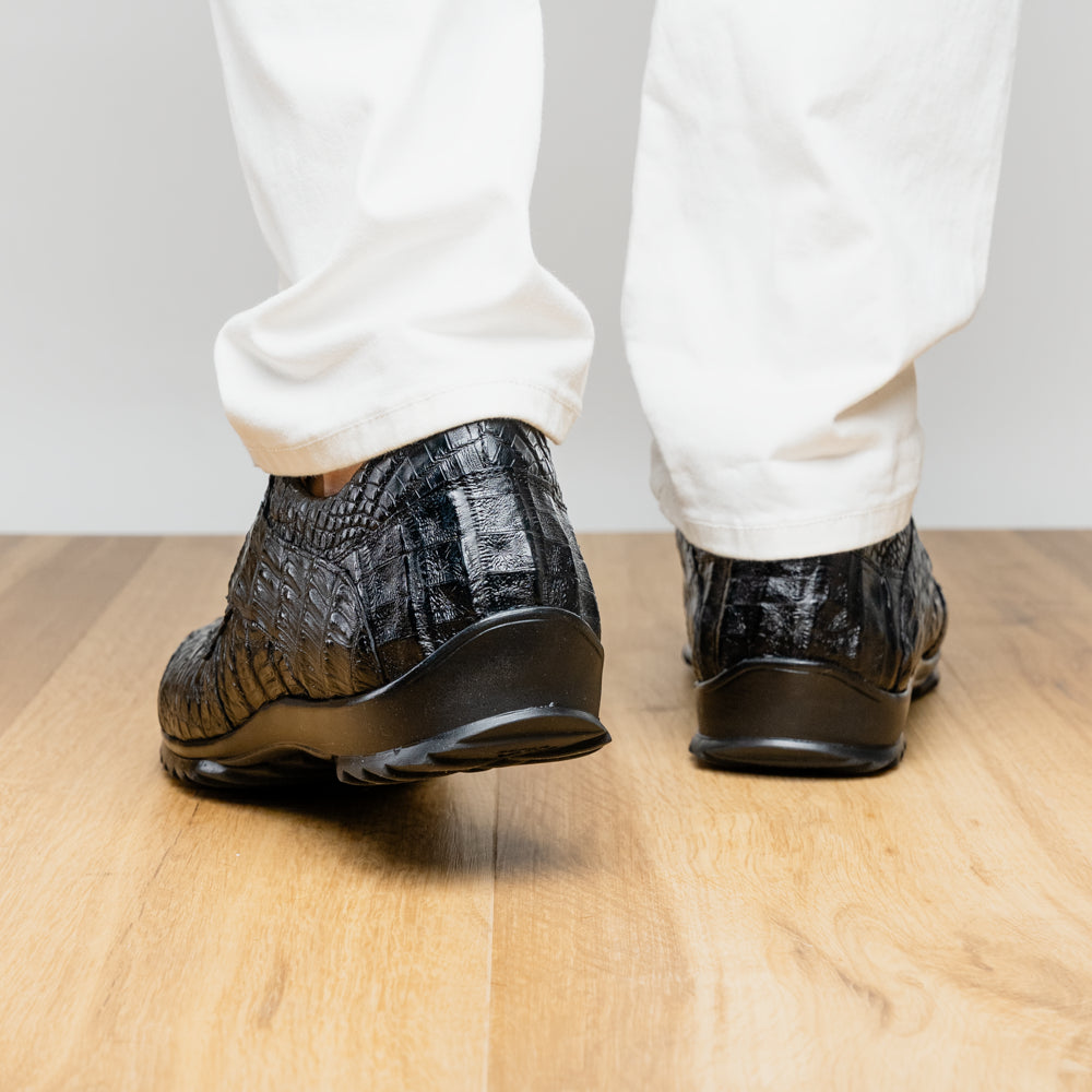 The Kratos Black by Marco Di Milano is a luxury black crocodile-patterned leather dress shoe, featuring a metal logo on the laces. Displayed with one upright and one on its side to showcase the detailed sole.