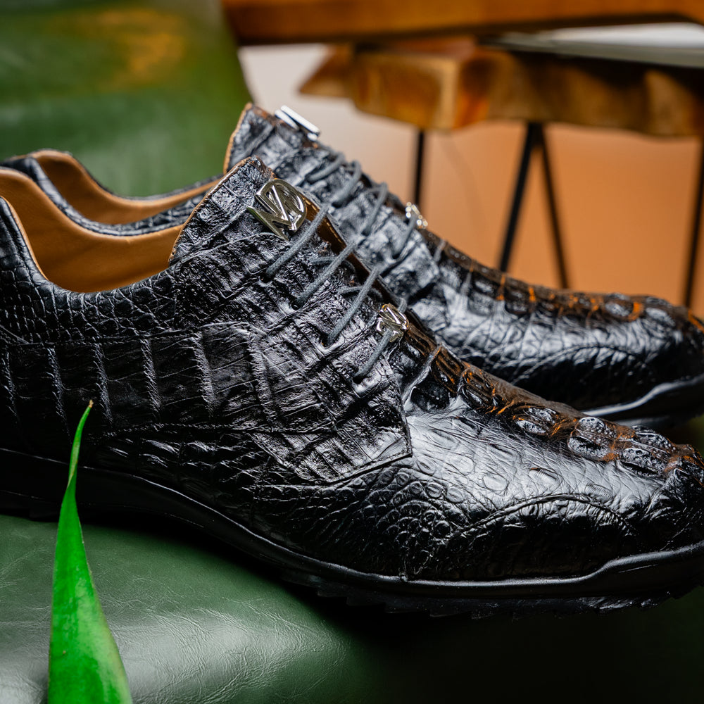 The Kratos Black by Marco Di Milano is a luxury black crocodile-patterned leather dress shoe, featuring a metal logo on the laces. Displayed with one upright and one on its side to showcase the detailed sole.