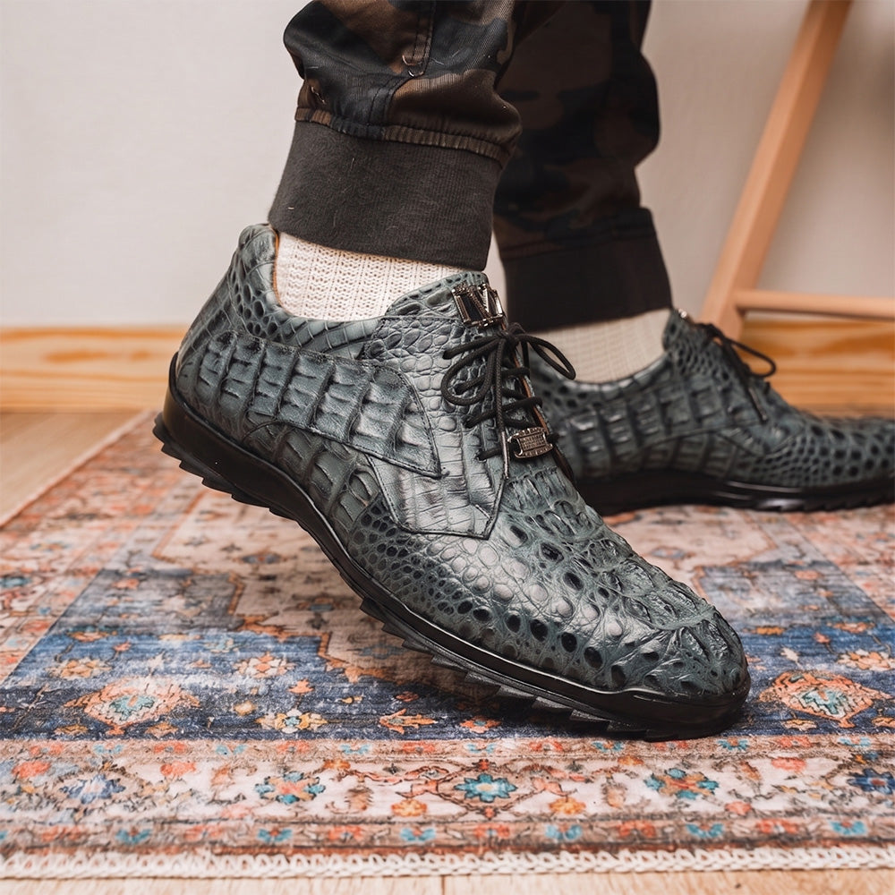 The Kratos Gray by Marco Di Milano are luxury dress shoes in textured gray crocodile-patterned leather with a hand-painted finish and black rubber soles; one shoe stands upright while the other rests on its side.