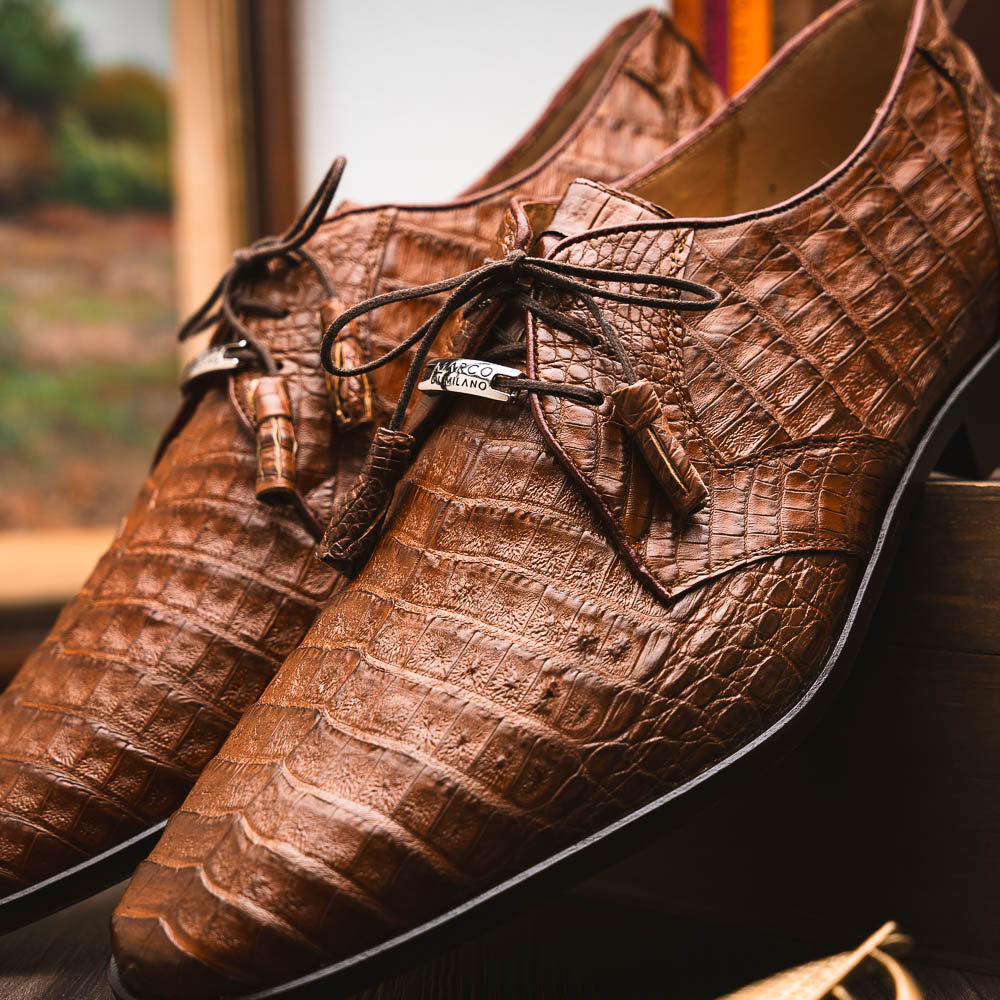 A pair of Marco Di Milano Lacio Bay Apache luxury derby shoes crafted from genuine caiman crocodile leather—one upright and the other on its side to showcase the exquisite sole.