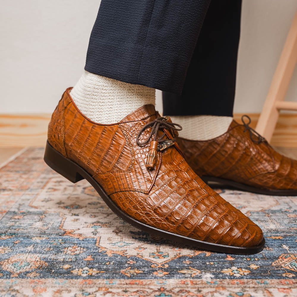 A pair of Marco Di Milano Lacio Bay Apache luxury derby shoes crafted from genuine caiman crocodile leather—one upright and the other on its side to showcase the exquisite sole.