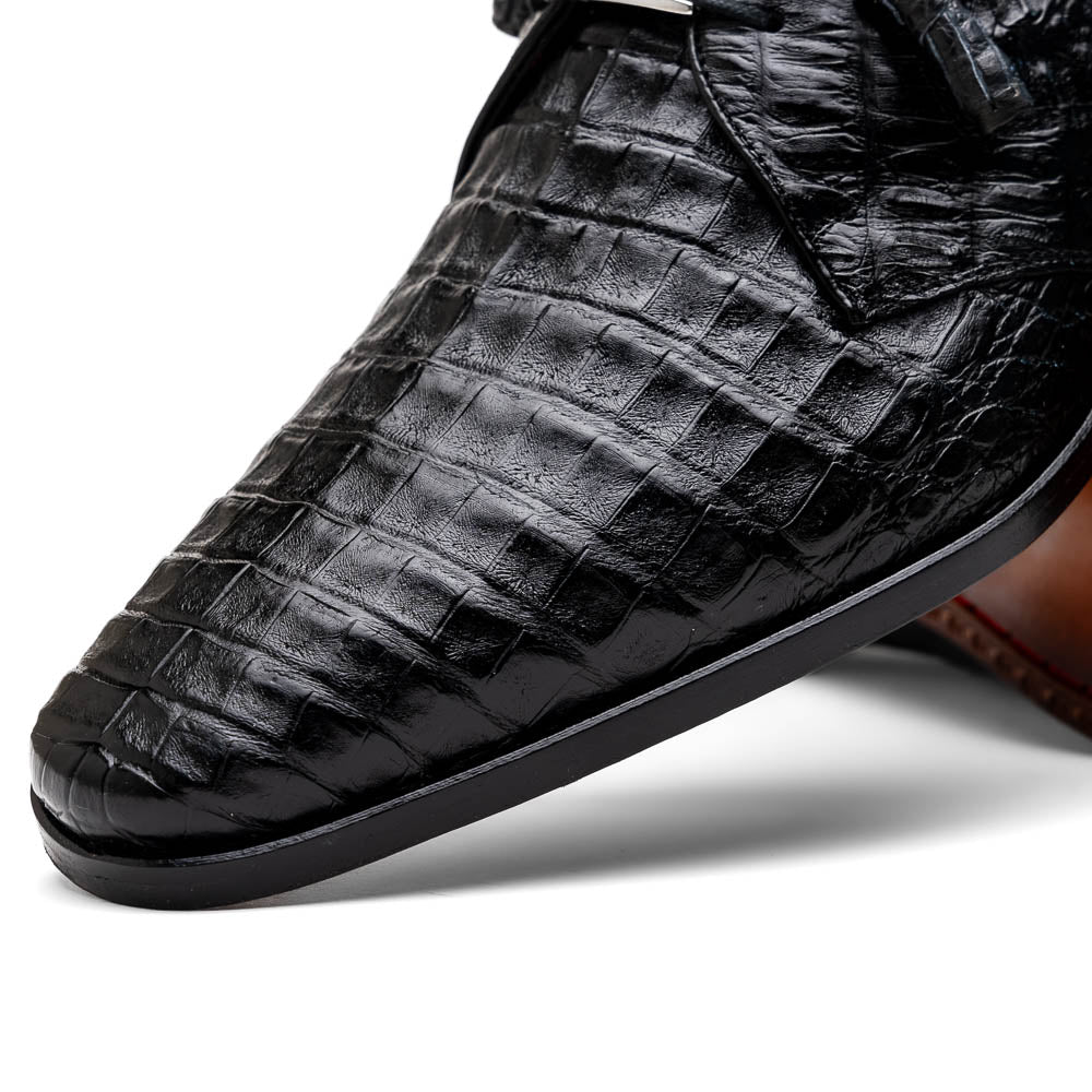 A pair of Marco Di Milano Lacio Black shoes—crafted from genuine caiman crocodile leather—one upright and one on its side, showing a brown leather sole embossed with luxury branding.