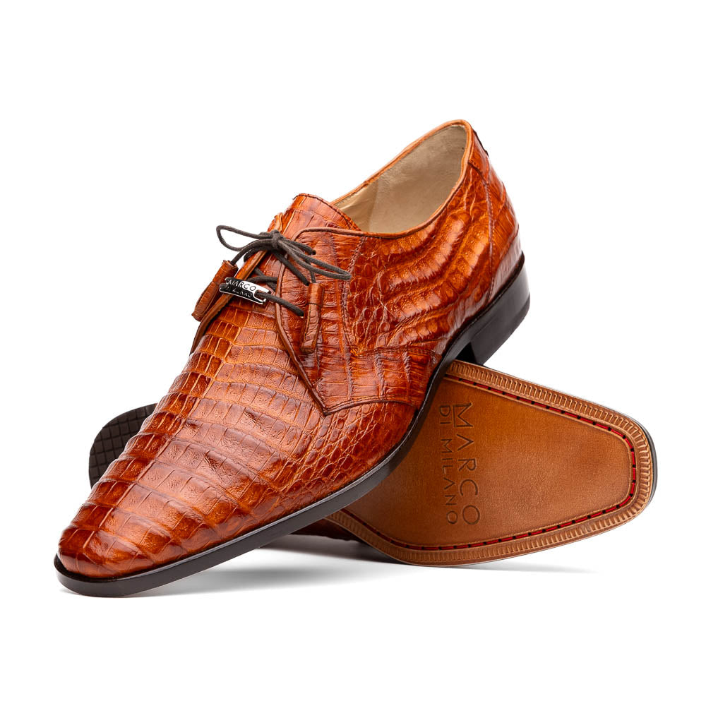 A pair of Marco Di Milano Lacio Brandy luxury derby shoes in a brown crocodile pattern, crafted from genuine caiman leather—one upright and one on its side to highlight the signature sole branding.