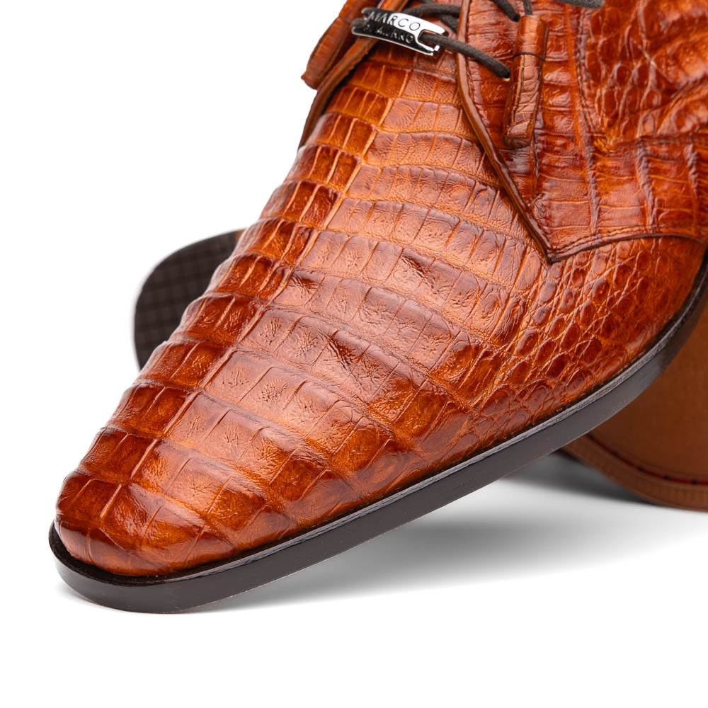 A pair of Marco Di Milano Lacio Brandy luxury derby shoes in a brown crocodile pattern, crafted from genuine caiman leather—one upright and one on its side to highlight the signature sole branding.