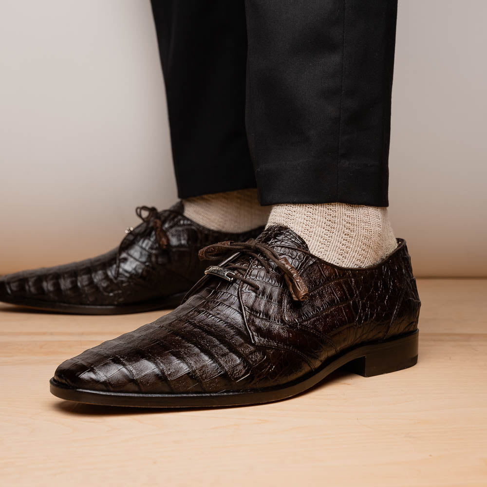 The "Lacio Brown" by Marco Di Milano is a luxury men's dress shoe made from genuine caiman crocodile leather, featuring tassel laces and the brand's logo—presented with one shoe resting atop the other.