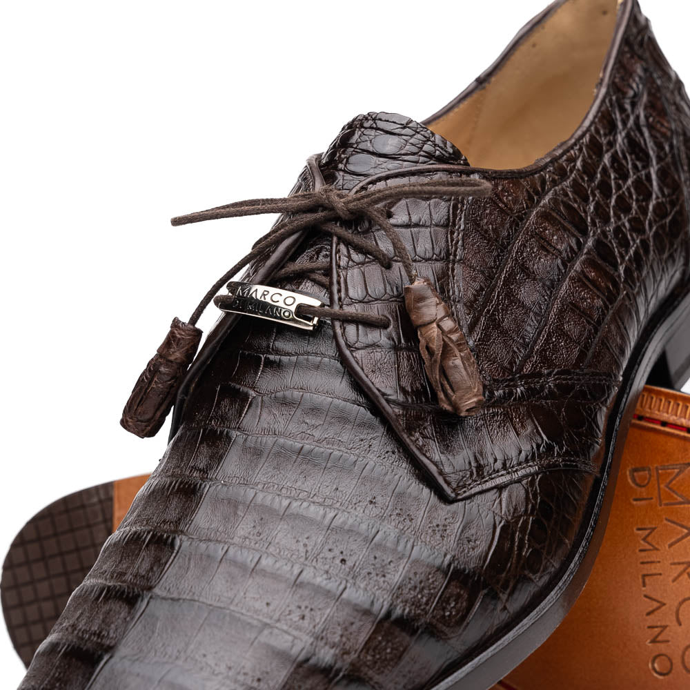 The "Lacio Brown" by Marco Di Milano is a luxury men's dress shoe made from genuine caiman crocodile leather, featuring tassel laces and the brand's logo—presented with one shoe resting atop the other.