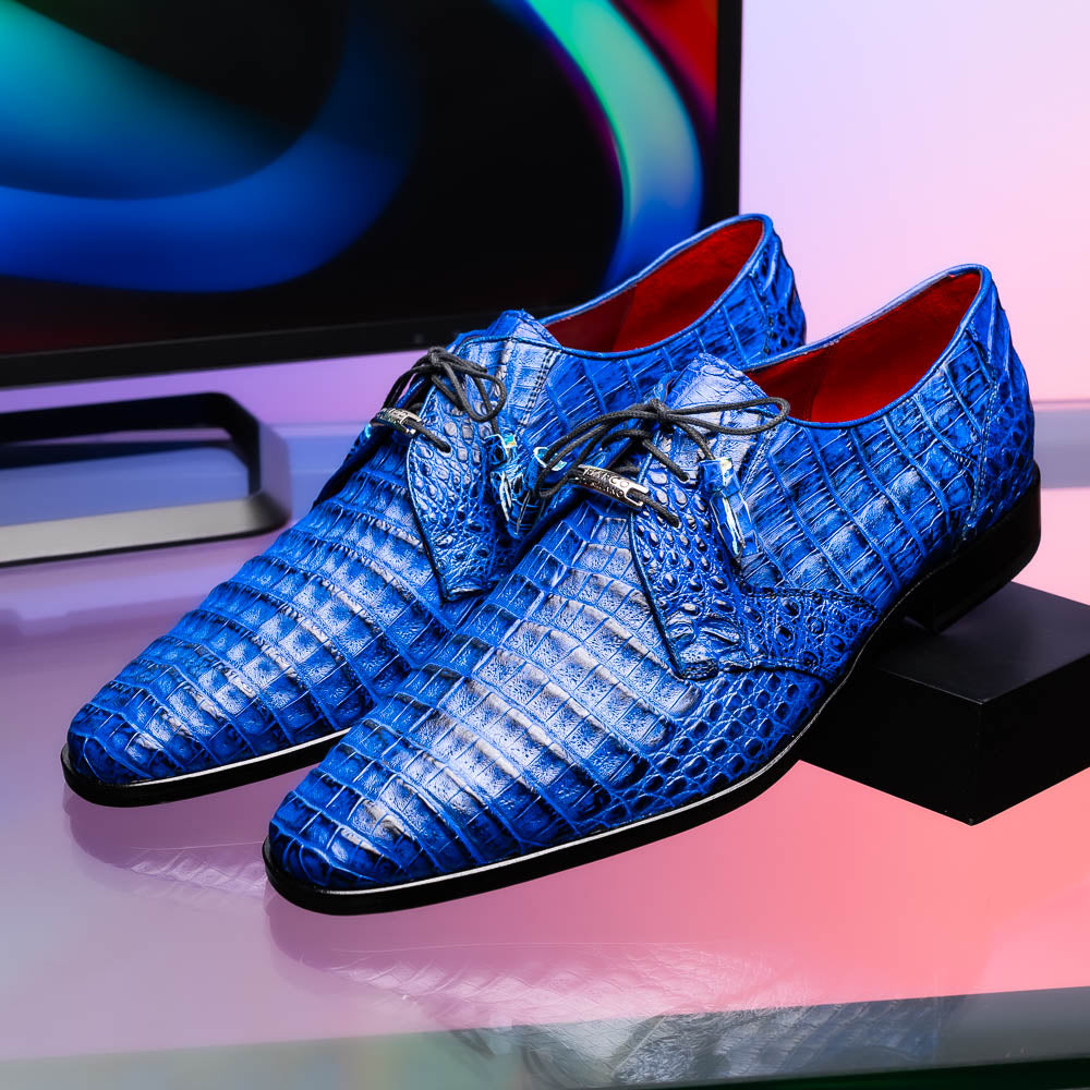 Marco Di Milano’s Lacio Electric Blue men’s dress shoes feature genuine caiman crocodile leather in blue, black laces, a bold red interior, with one shoe standing upright and the other lying on its side.