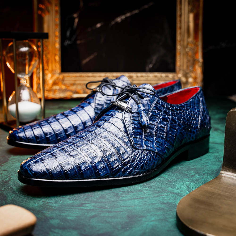The Lacio Navy by Marco Di Milano are luxury dress derby shoes made from genuine caiman crocodile leather, featuring elegant tassels, a red interior lining, and tan leather soles stamped with the brand’s name.