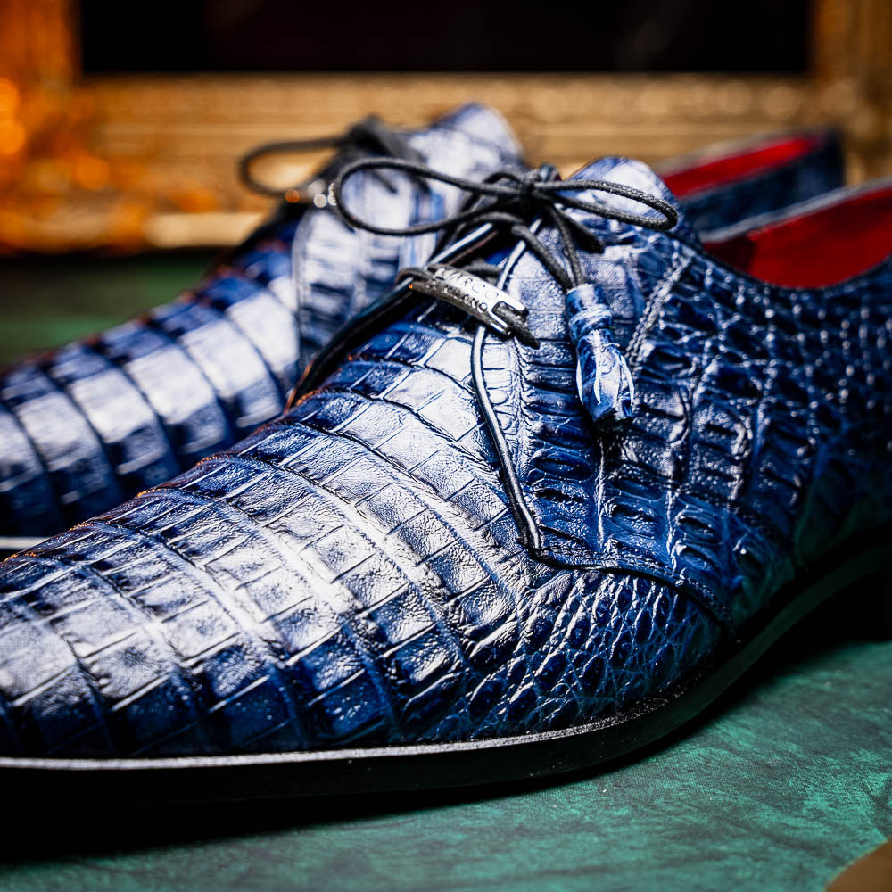 The Lacio Navy by Marco Di Milano are luxury dress derby shoes made from genuine caiman crocodile leather, featuring elegant tassels, a red interior lining, and tan leather soles stamped with the brand’s name.