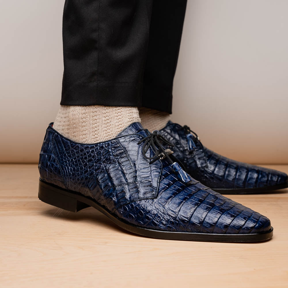 The Lacio Navy by Marco Di Milano are luxury dress derby shoes made from genuine caiman crocodile leather, featuring elegant tassels, a red interior lining, and tan leather soles stamped with the brand’s name.