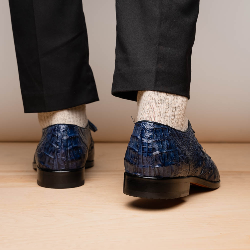 The Lacio Navy by Marco Di Milano are luxury dress derby shoes made from genuine caiman crocodile leather, featuring elegant tassels, a red interior lining, and tan leather soles stamped with the brand’s name.